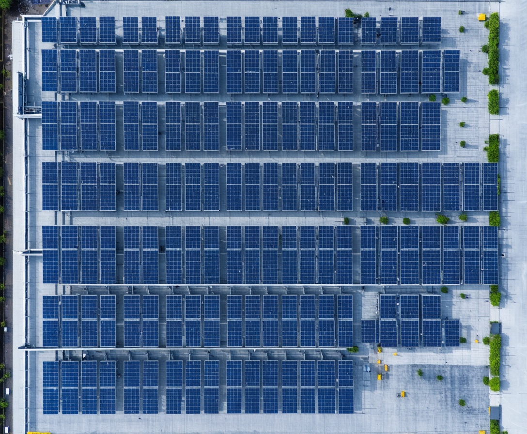 Aerial drone view of a massive solar farm installation on the roof of a large modern factory